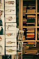 Shelf of unread books with perfect spines next to library card on nightstand
