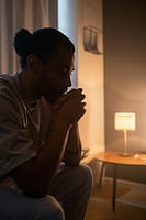 Person sitting alone at night thinking about money and life choices
