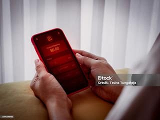 Person looking at smartphone showing zero bank balance with worried expression