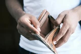 Person holding an open empty leather wallet showing financial struggle before starting a no spend challenge
