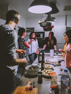 group of friends cooking together at home laughing and having fun