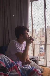 person sitting by window with coffee feeling peaceful about finances