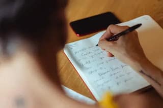 person calmly writing in notebook with pen feeling in control of money