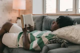 person sitting on couch reading a book peacefully on a weekend